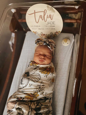 Baby wrapped in floral swaddle with matching bow
